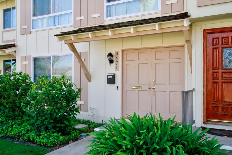 A DOOR CLOSED AND THE BUILDING LOOKS LIKE MEDIUM SIZE BUNGALOW AND BALCONY ALSO AT THE FIRST FLOOR AND SMALL PLANTS ALSO NEAR TO THERE AT THE MORNING TIME