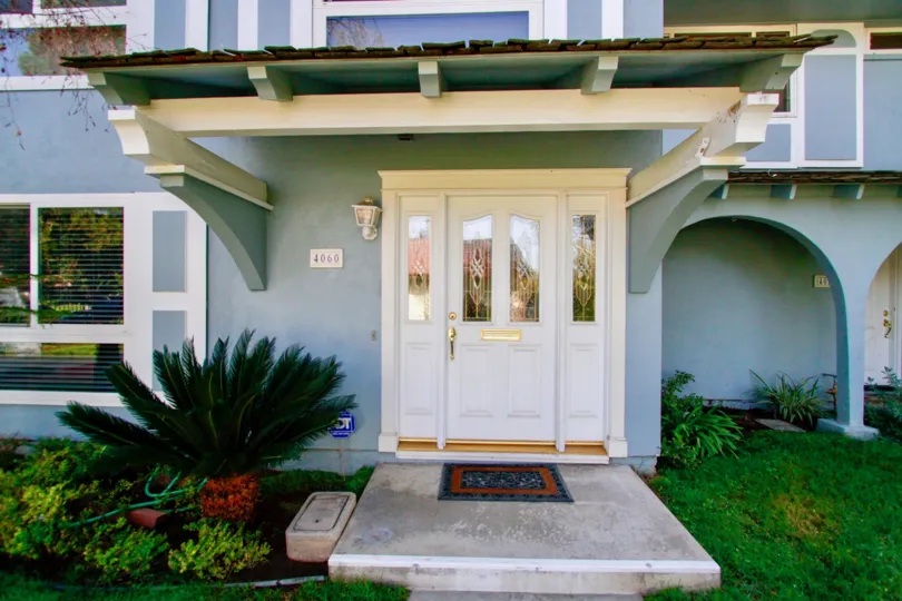 A HOUSE WITH A LONG DOOR AND IT CLOSED AND SOME PLANTS AND GRASS ALSO IN FRONT OF THE PLACE