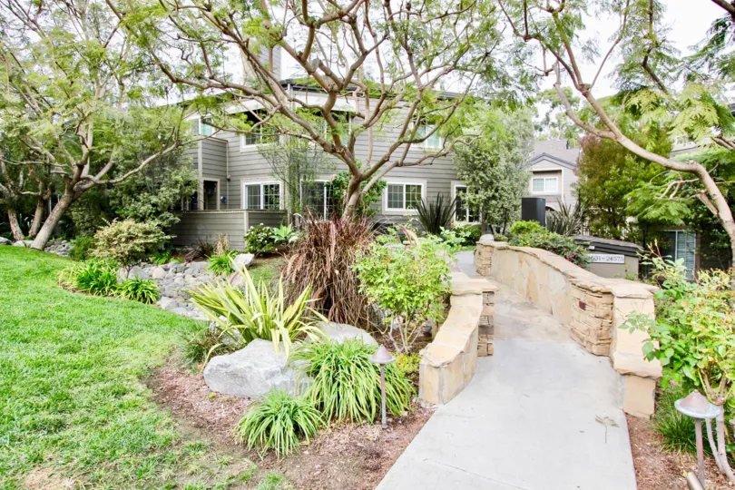 THE RESIDENCY IN THE BLUFFSIDE VILLAS WITH THE ROCK, PATHWAY, LAWN, PLANTS, TREES