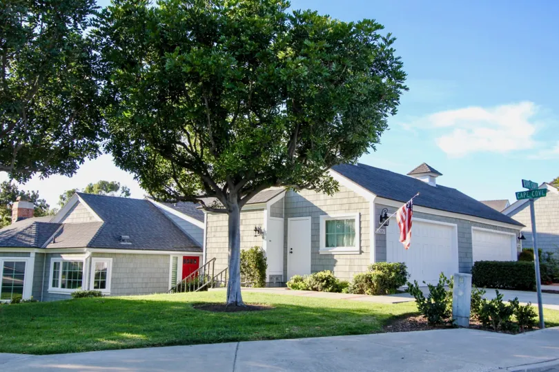 a sunny day in the cape cove with a building that has tree in front and a flag and sign board at right