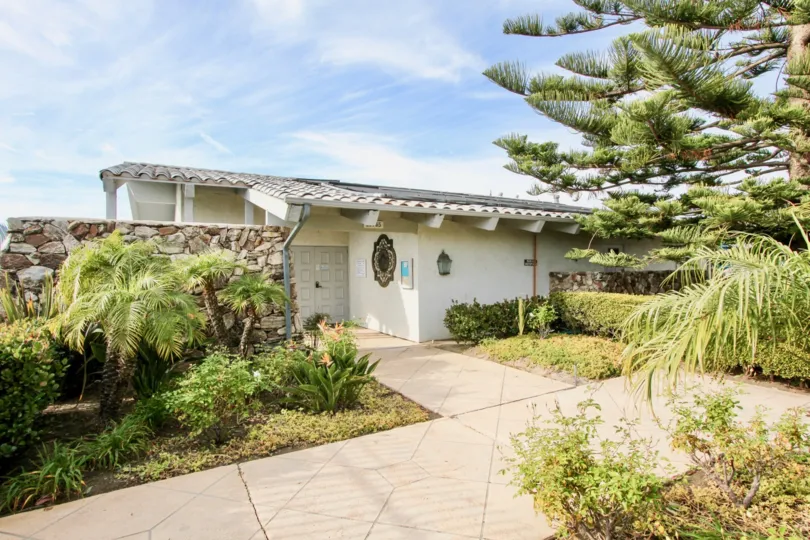 a sunny day in the dana bluffs with house that has stone walls and garden of trees