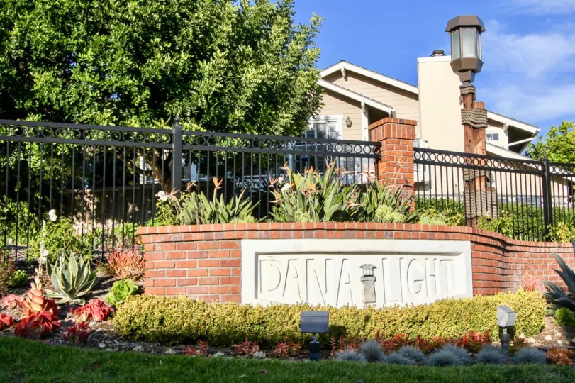 a sunny day in the dana light l with house that has lamp post and garden in left