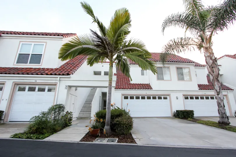 Front view with trees, garage door and staircase of Encantamar community, Dana Point, CA