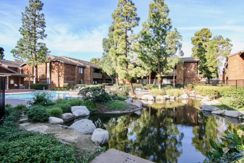 a sunny day in the harbor creek with buildings in bricky style and small pond with garden around