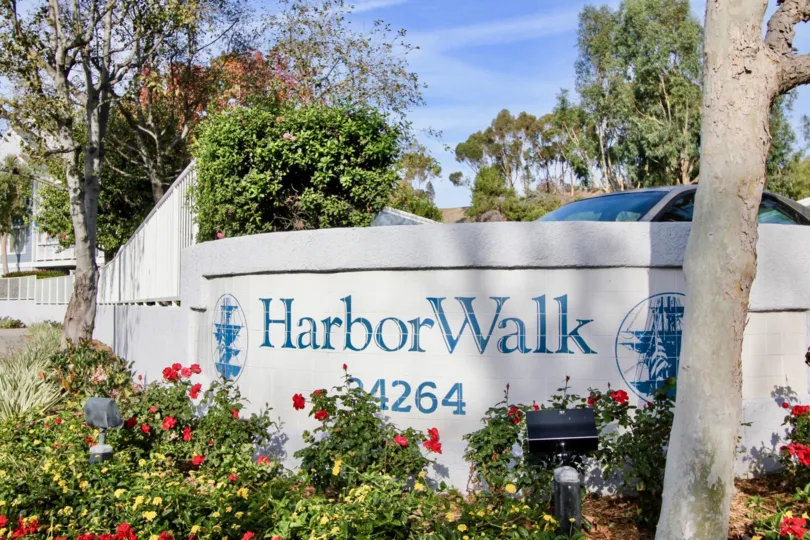 A sunny day in the Harbor Walk with a sign on the wall and car.