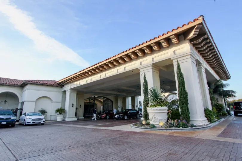 A sunny day in the Sea Villas at St. Regis with some cars in front of a building.