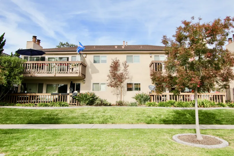 a sunny day in the spindrifter condos with a building that has large garden in front and a umberrla on the balcony