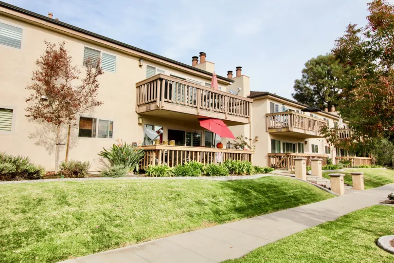 a warm day in the spindrifter condos with a building that has garden around and a umberrla in front of the entrance