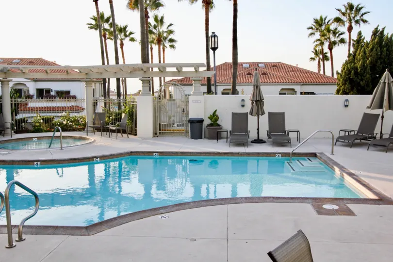 a sunny day in the tennis villas with a building that has swlming pool with chair and resting table