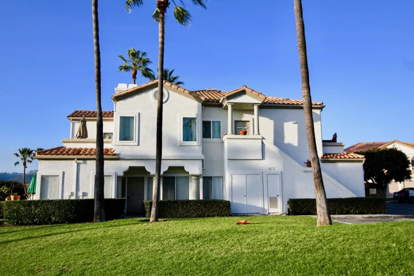 A sunny day in the Tennis Villas with some palm trees and a building.