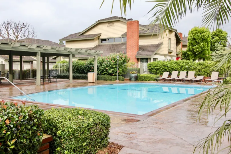 Concord Place pool with deck chairs and trimmed bushes on a cloudy day.