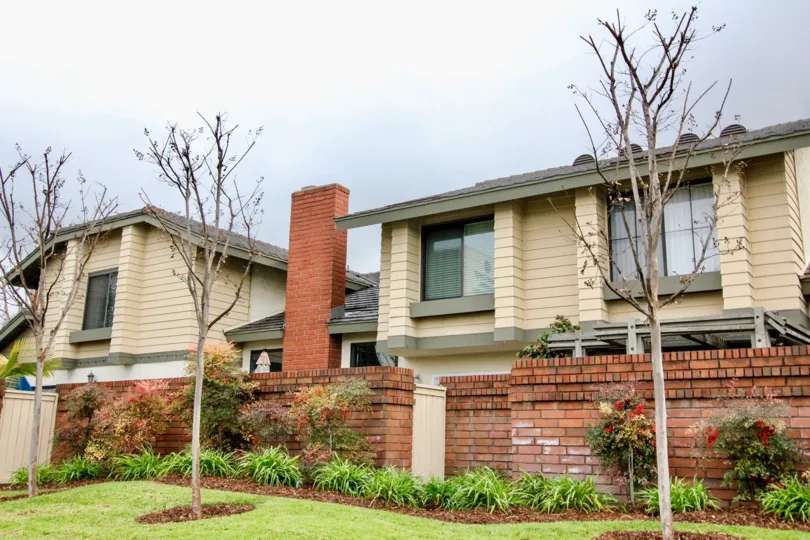 Concord Place Fountain Valley California brick shaped walls with thin branched trees without leafs in front
