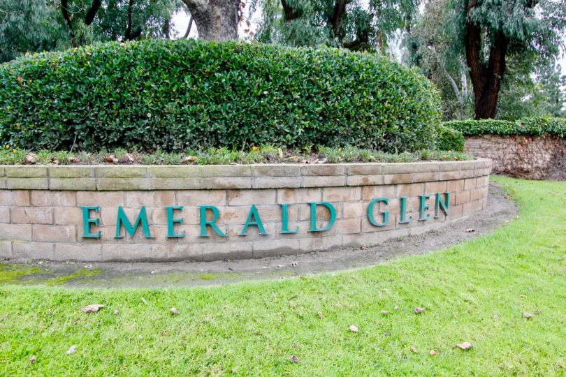 An entrance area with bushes on top and writtien with green letter showing the community Emerald Glen.