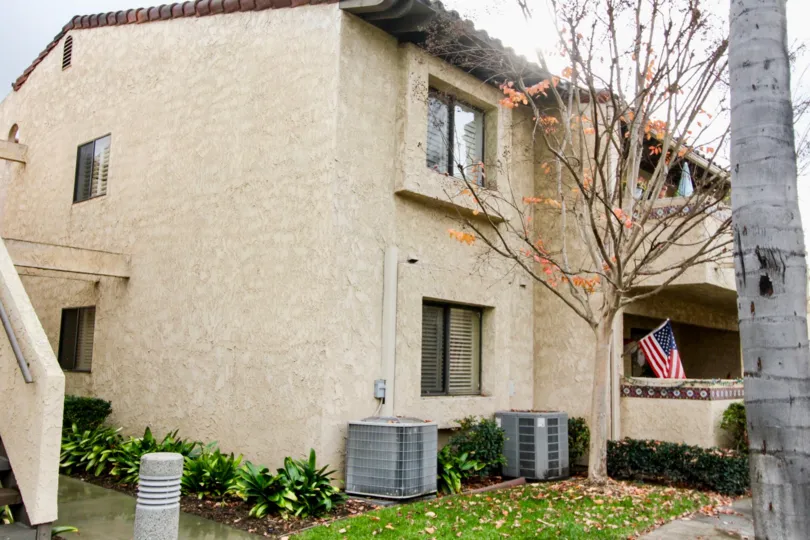 Dark tan housing with projected window areas outside with some plants and trees located in Fountain Crest community.