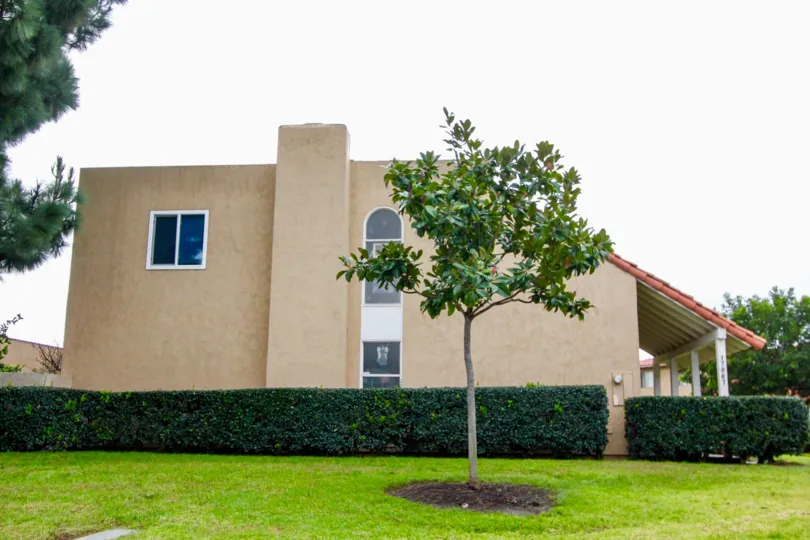 Outer View of a house in Green Valley Townhomes with side view of building and garden.