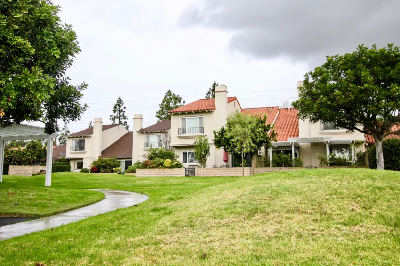A long and winding sidewalk leads to multiple condo buildings at Green Valley Warner Village in Fountain Valley CA