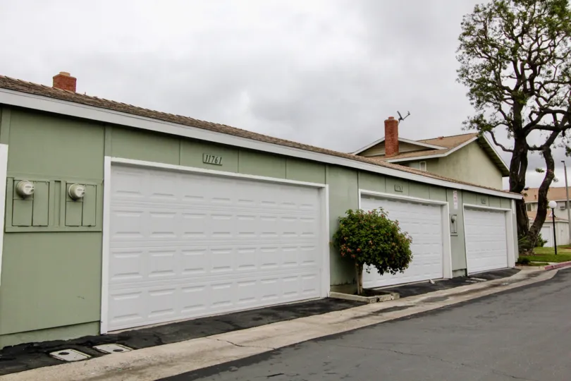 The whiteand grey color houses in the Harbor Valley with ornamental plants and big trees near the road side.