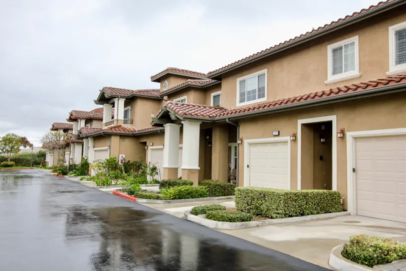 Long row of tan residential homes with garages which are well taken care of in Liberty Founder of Village community.