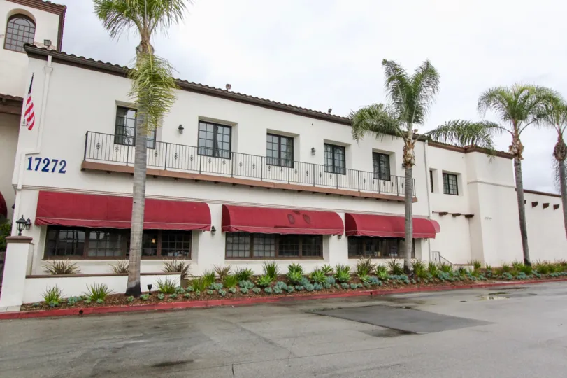 A building with maroon onning with large windows in Los Caballeros community.