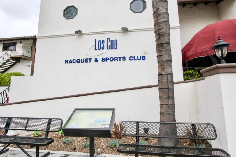 Los Cab Racquet & Sports Club sign in the color blue and background cream located in Los Caballeros community.