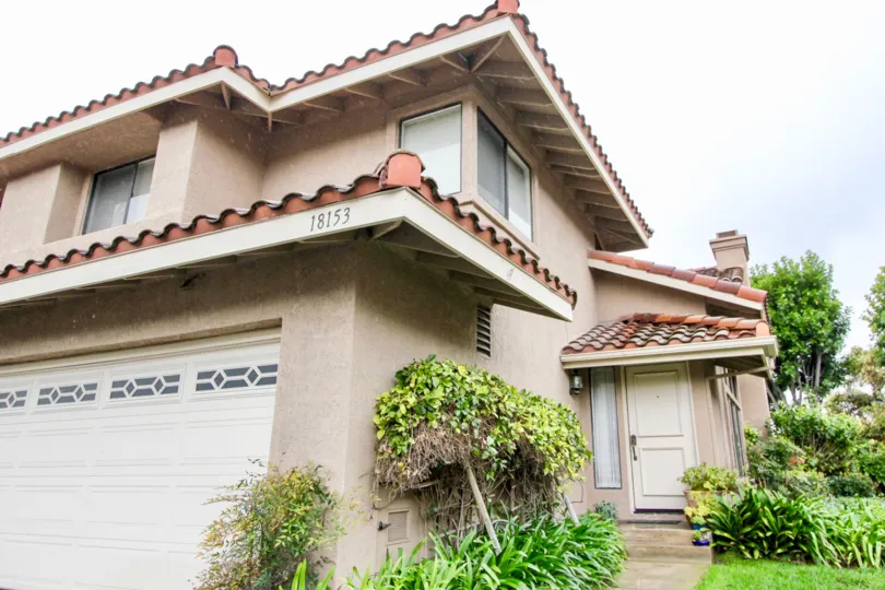 A beautiful grey building with number 18153 in the Mariposa with green grass, trees and shrubs.