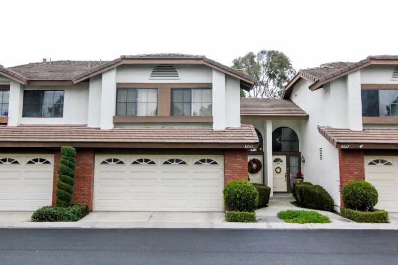 A long paved road sits in front of a two story home with two garages in Shadow Lane in Fountain Valley CA