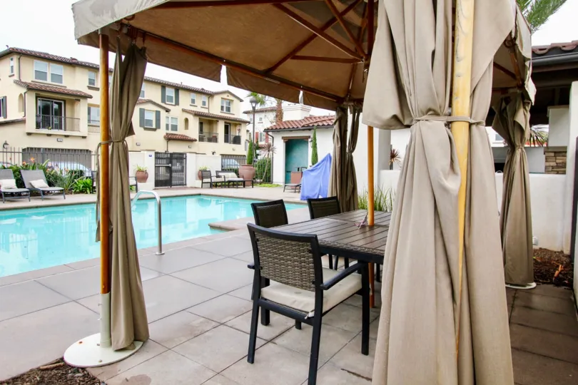 A swimming pool in the Solana Walk with beautiful buldings, resting room with chairs and tables, shrubs.