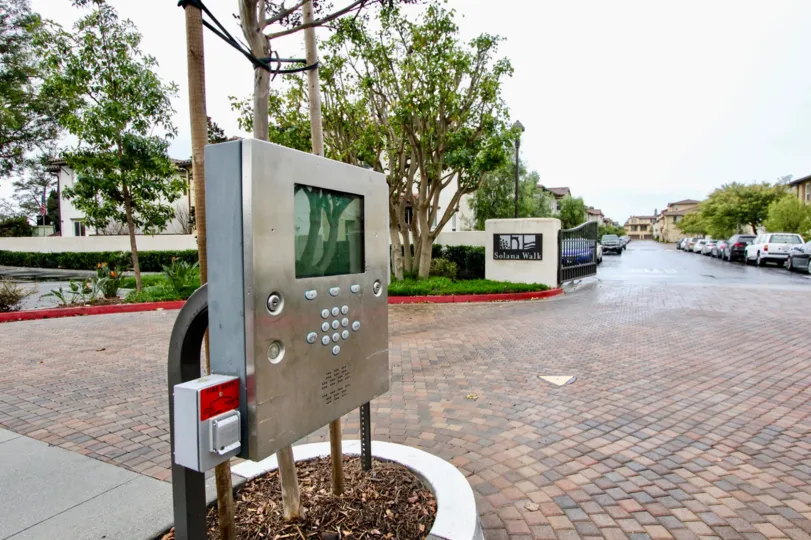 at the road in Solana walk has telephone booth with trees, lawn and plants