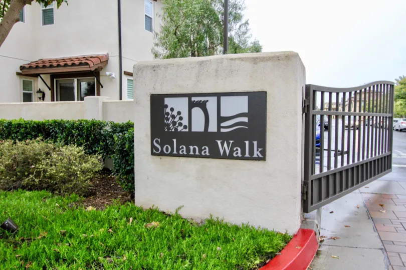 Front to the gate in Solana walk has grasses with trees and cutting bushes at fountain valley city