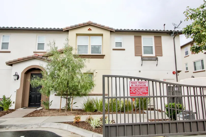 Open metal gate to a residential home that is tan and brown in Solana Walk community.