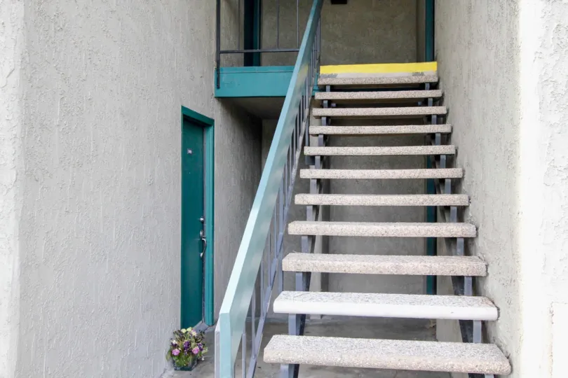 Gray stucco open stairwell leads to turquoise doors in Brea Country community of Fullerton, CA.
