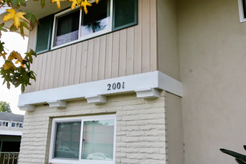 Two floor apartment with room number and trees also located at the front
