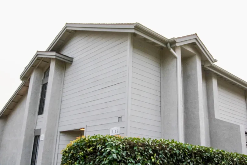 A apartment building of Chapman Villas with gray siding on a cloudy day.