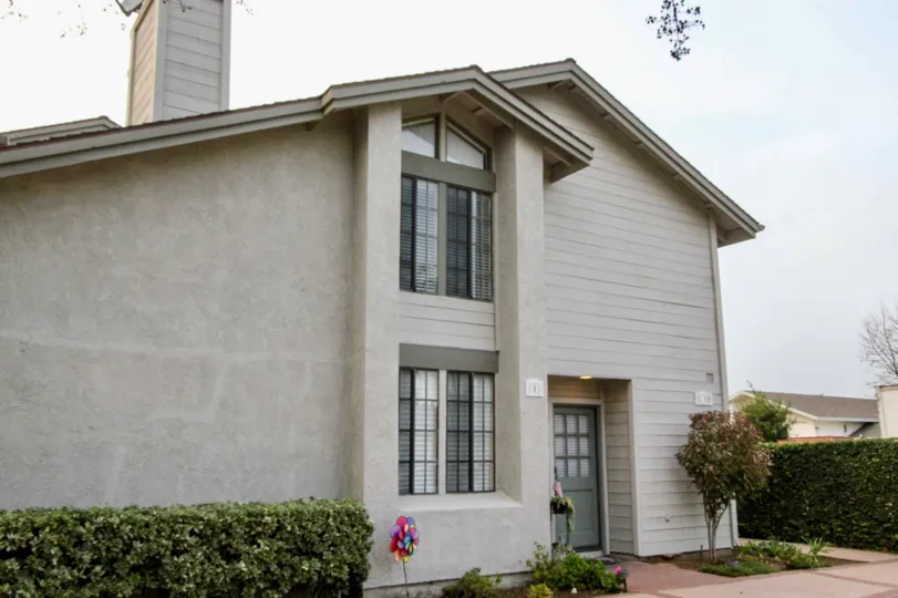 A home in the Chapman Villas community with a walkway and trimmed bushes.