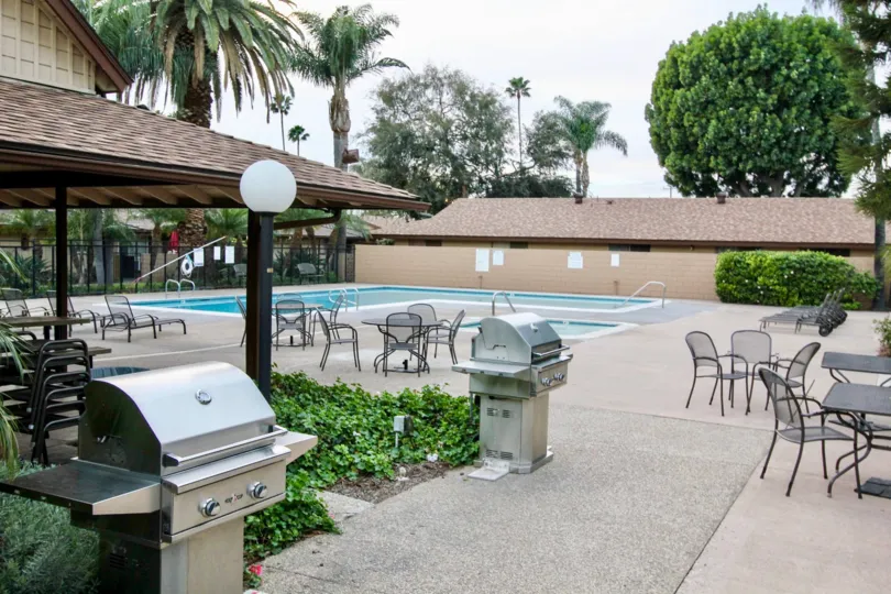 The swimming pool in the Coco Palms with buldings, resting chairs, small ornamental plants, big palm trees and shrubs.