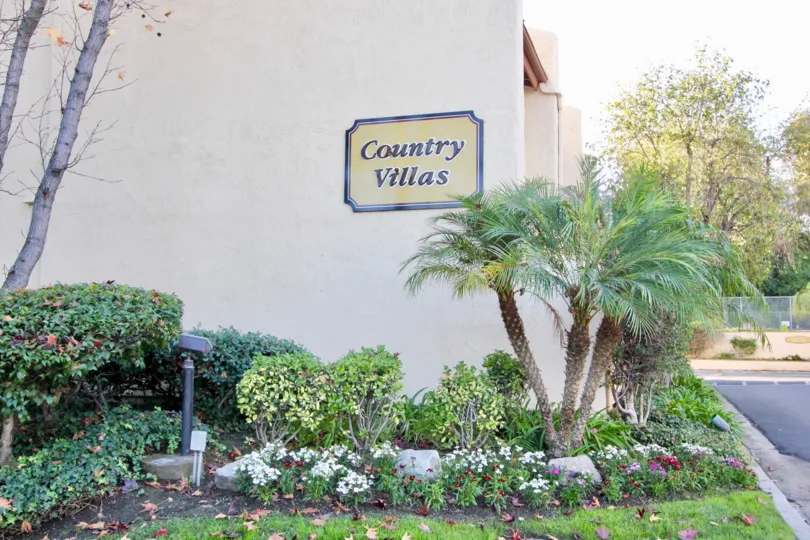 A sign for the Country Villas community with assorted plants in a garden.