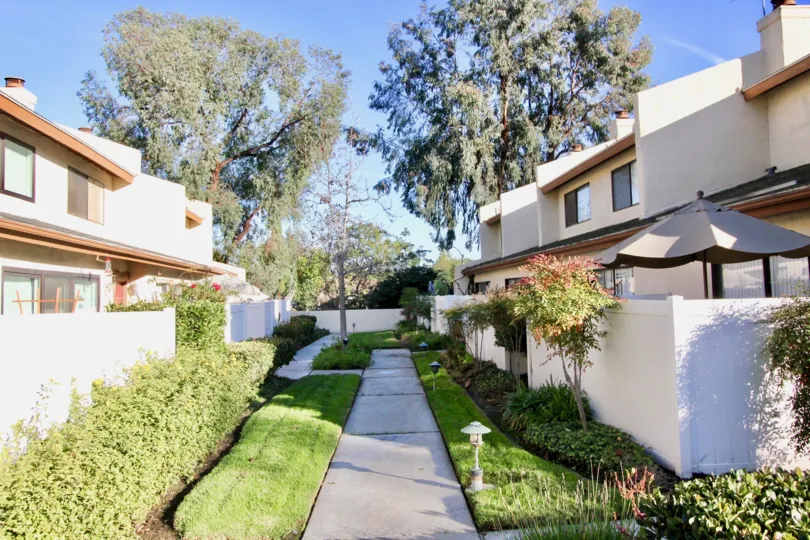A beautiful day in the Country Villas with a path between buildings.