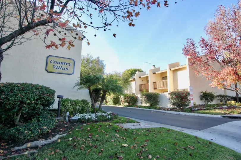 Entrance to the Country Villas with a sign and trees on a sunny day.