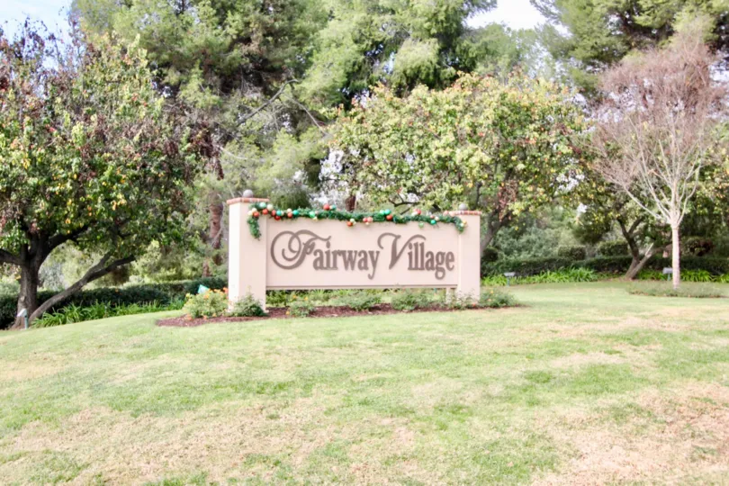 A day in the Fairway Village in front of a sign with decorations.