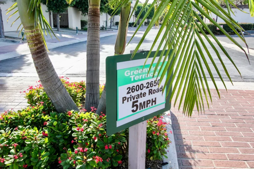 Speed limit sign in Greenview Terrace with palm trees and flowers.
