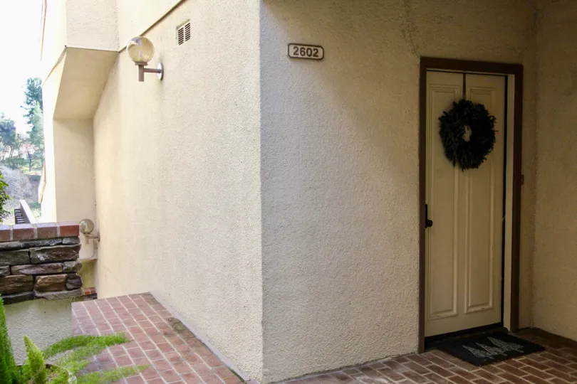 Door to a Greenview Terrace apartment with a Christmas wreath and stone fence.