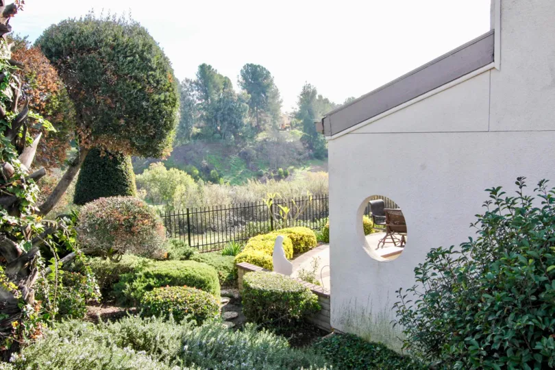 Backyard of a Greenview Terrace home with bushes and trees.