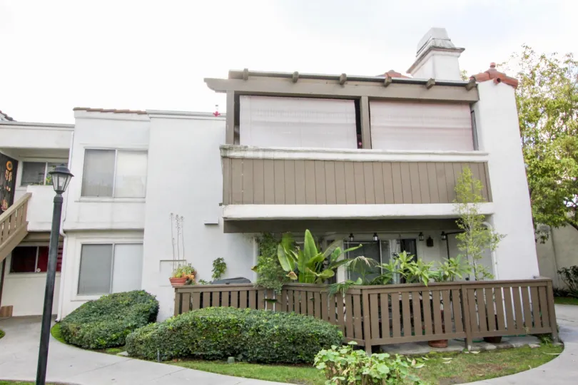A two story apartment building of Heritage Fullerton with a patio and staircase.