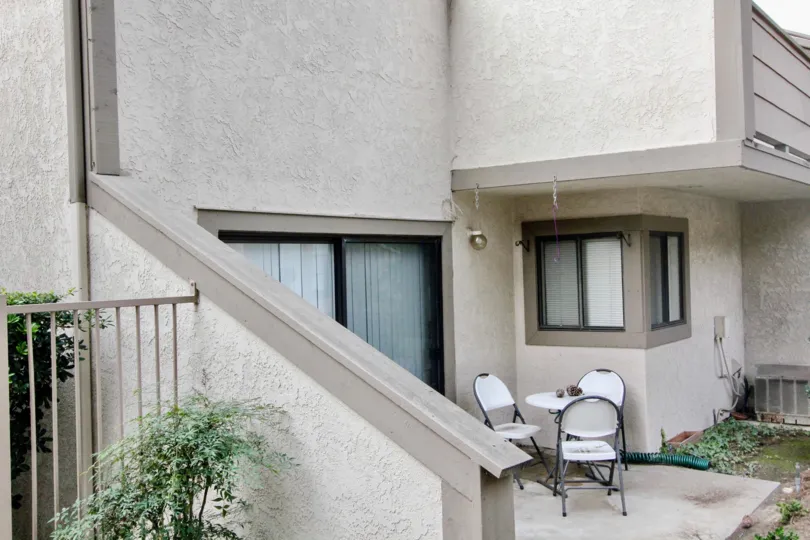 A beautiful grey house in the Hidden Lakes with glass windows, green grass and shrubs, resting chairs.