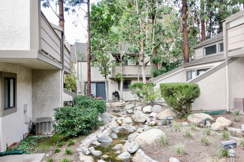 Backside of the house in Hidden Lakes has tallest trees than buildings with rocks and water