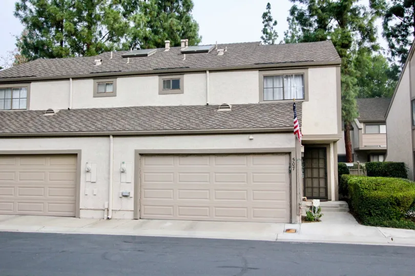 A apartment building in the Hidden Lakes community with garages and a flag.