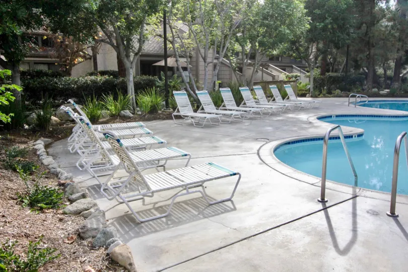 A beautiful day in the Hidden Lakes with a swimming pool and chairs.