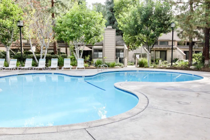 The pool in the Hidden Lakes community with deck chairs and lamps.