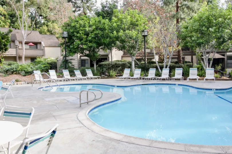 Between the Villa's in Hidden lakes, Swimming pool with seating chairs, trees and bushes are present