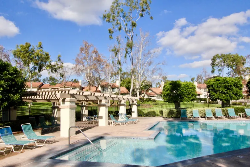 Outside of swimming pool has seating chairs and plants and trees with lawn in Malvern Creek